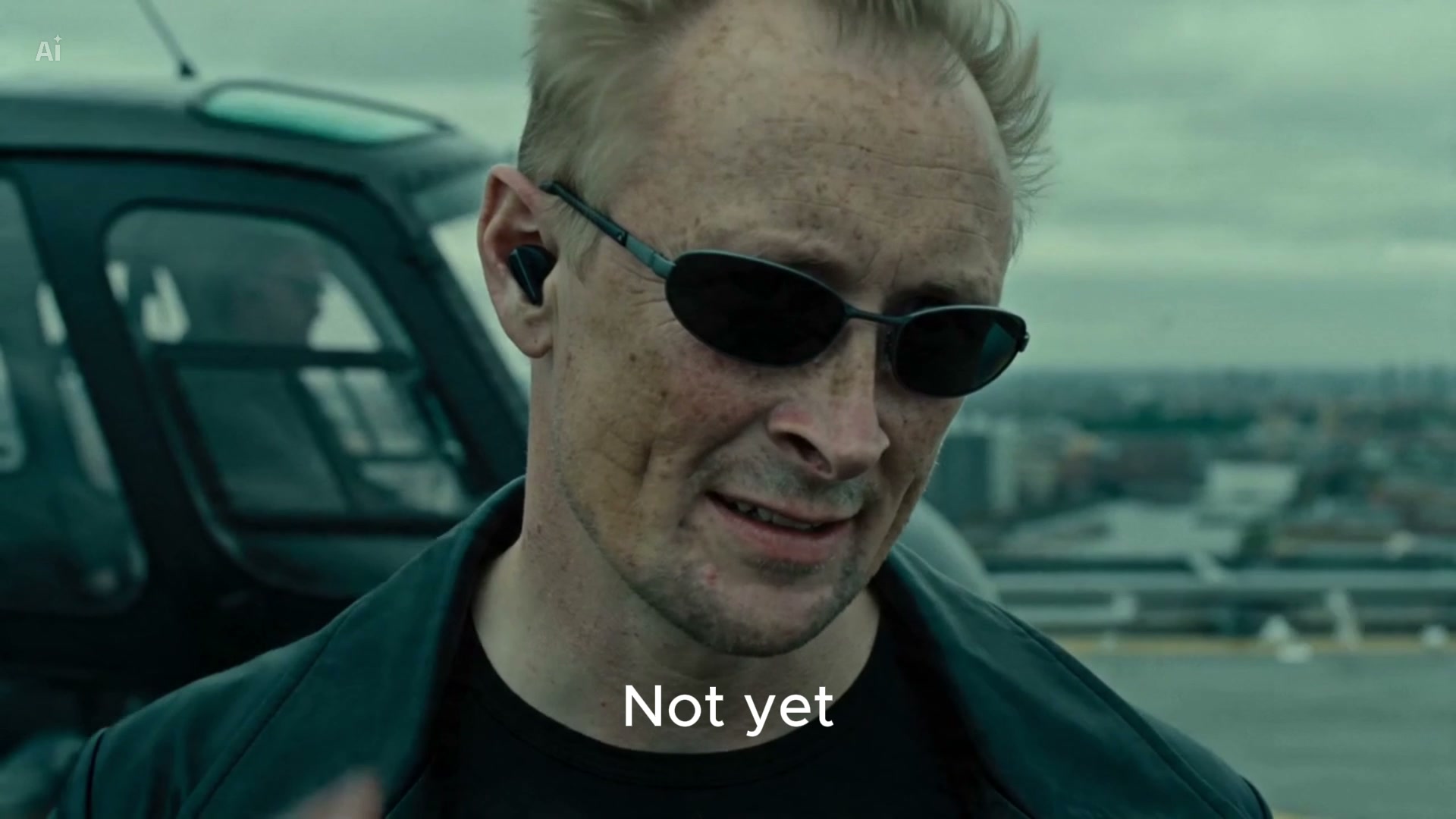 Close-up of the restyled character in Matrix coat and sunglasses on the rooftop, helicopter behind